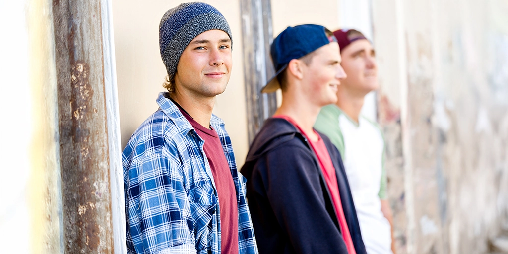 A group of teenage boys standing casually outdoors, symbolizing social interactions and the pressure to conform for individuals with autism.
